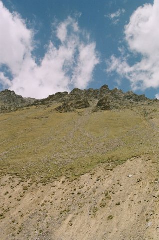 About 2/3 of the way up the grass section in the middle is a black dot. A Tibetan strutting his back yard. This face stemmed straight up from the edge of the road. Ridge is around 5000mts.